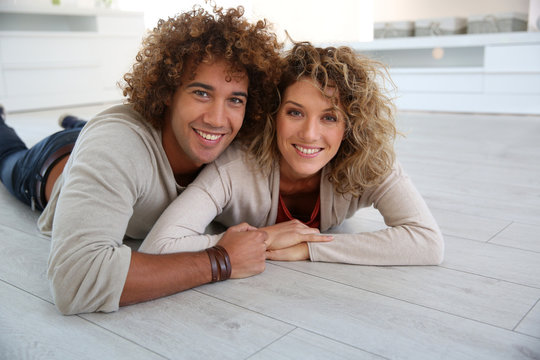 Cheerful couple laying down on wooden floor