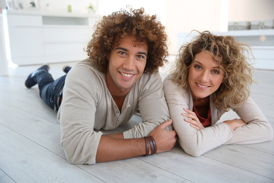 Cheerful couple laying down on wooden floor