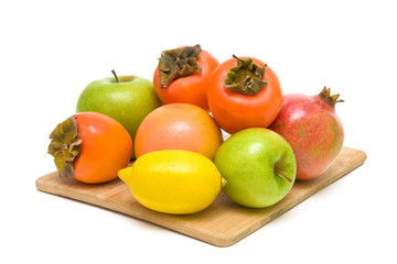 fruit on a wooden cutting board on white background