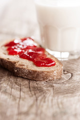 Bread with strawberry jam and milk in glass