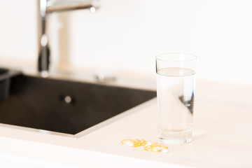 Pills and glass of water on countertop