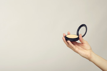 Close up of woman hand holding a make up mirror, make up powder