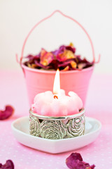 Beautiful spa setting with pink candle and rose petals.