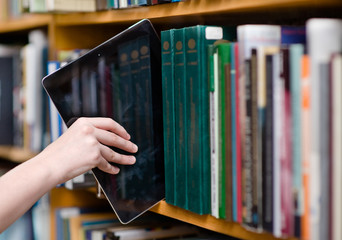 closeup hand putting a tablet pc in the shelves in the library