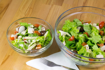 Two bowls of fresh vegetable salad served on a wooden table