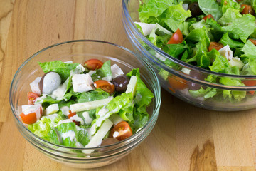 Two bowls of fresh vegetable salad served on a wooden table