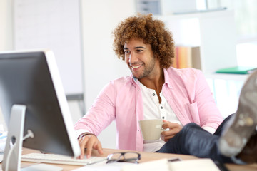 Young smiling man in office with feet on desk