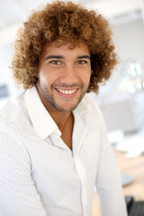 Cheerful man sitting on desk in office