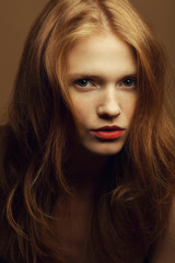 Fototapeta premium Emotive portrait of a fashionable model with red wavy hair