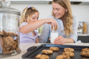 Woman with daughter dipping cookie in milk