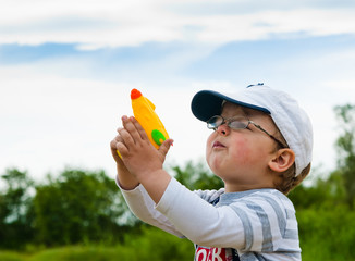 Little boy plays with a water pistol