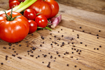 Red tomatoes with pepper and garlic on old wooden table