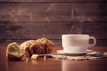 Cup of hot coffee with cake on wooden background
