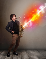 Young man playing on saxophone with colorful sound waves
