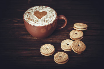 Cup of coffee decorated with heart and cookies.