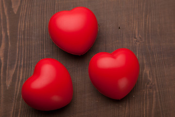 three rubber hearts on wooden background