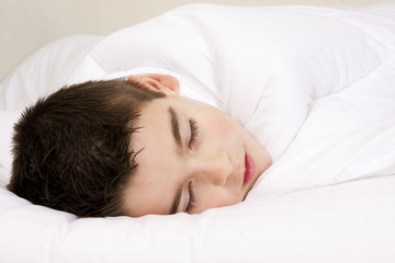 Fototapeta na wymiar Little boy in bed covered with blanket