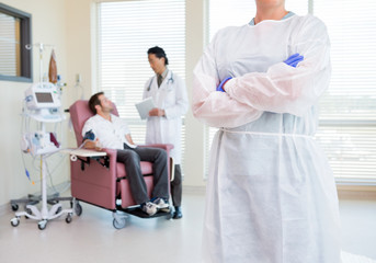 Nurse Standing Arms Crossed While Doctor Examining Patient's Hea