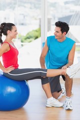 Fototapeta na wymiar Male trainer helping woman with her exercises at gym