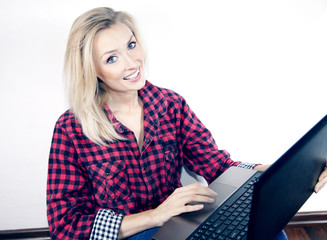 Cheerful young blonde girl using notebook.