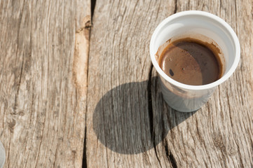 white plastic glass of coffee on a wooden table