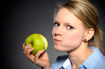 junge blonde Frau mit einem grünen Apfel