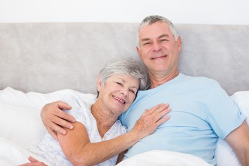 Senior man embracing woman in bed