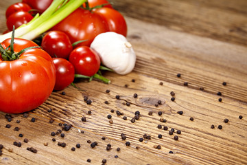 Red tomatoes with pepper and garlic on old wooden table