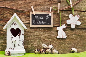 Osterdekoration an Holzwand mit Tafel, Frohe Ostern