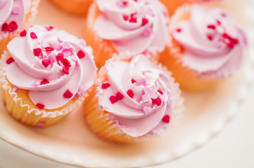 Cupcakes with pink cream and heart sprinkles