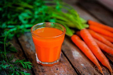 Fresh-squeezed carrot juice on wooden background