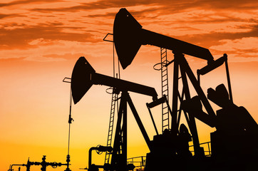 Silhouettes of oil pumps at dawn sky background