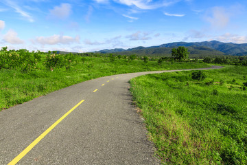 Beautiful countryside road in green field under blue sky