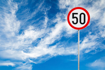 Round speed limit road sign above blue cloudy sky