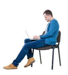 Side view of a man sitting on a chair to study with a laptop.