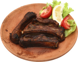 Traditional grilled pork ribs on the grill with fresh vegetables