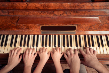 Fototapeta na wymiar Rodzina z trzech osób gra na fortepianie, widok z przodu