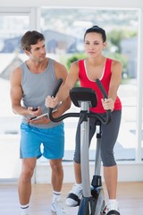 Obraz premium Fit woman with male instructor working out at spinning class