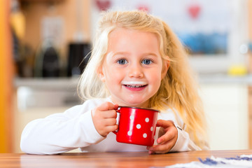 Mädchen trinkt Milch in der Küche