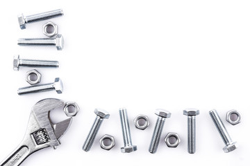 Screws, nuts and spanner on white background