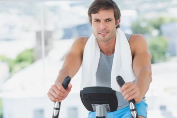Fototapeta na wymiar Smiling man working out at spinning class in bright gym