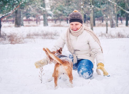 Woman playing with her pet in winter park