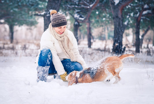 Happy woman playing with her pet in snow