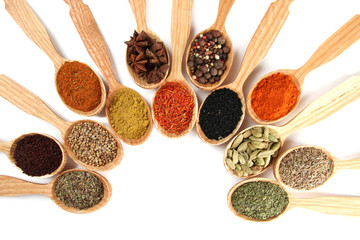 Assortment of spices in wooden spoons, isolated on white