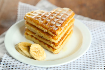 Sweet Belgium waffles with banana, on wooden table background