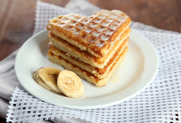 Sweet Belgium waffles with banana, on wooden table background