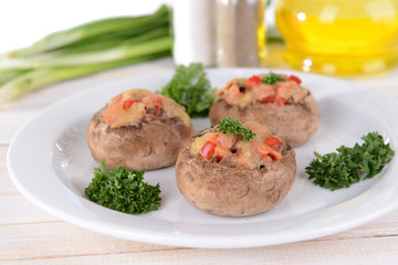 Stuffed mushrooms on plate on table on light background