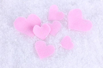 Little felt hearts on snowy background
