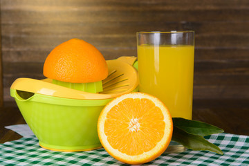 Citrus press and oranges on table on wooden background