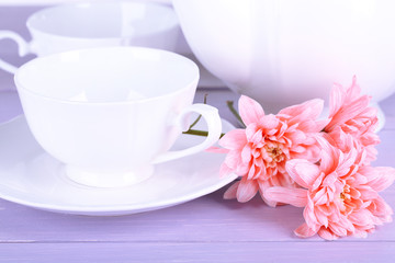 Obraz na płótnie Canvas Pink chrysanthemums with tea service on wooden table